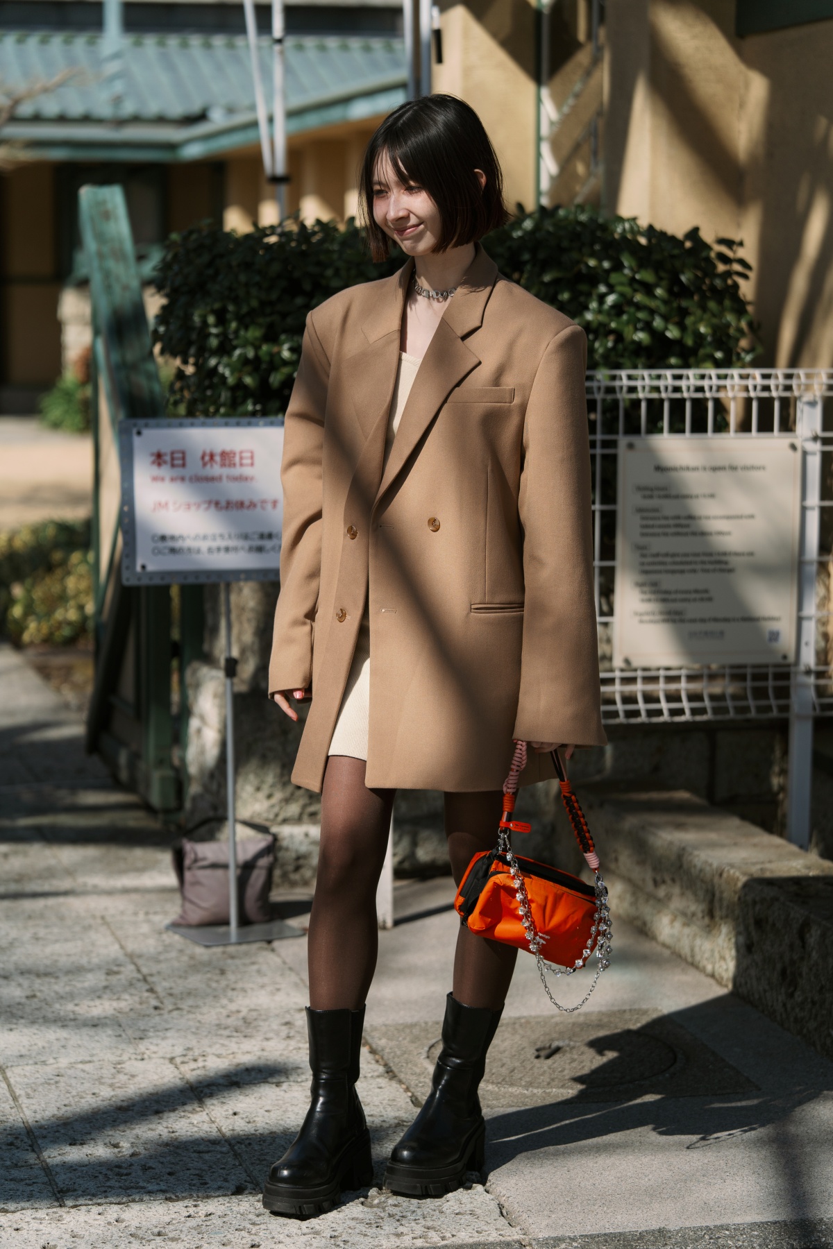 A imagem mostra uma mulher fotografada enquanto anda na rua