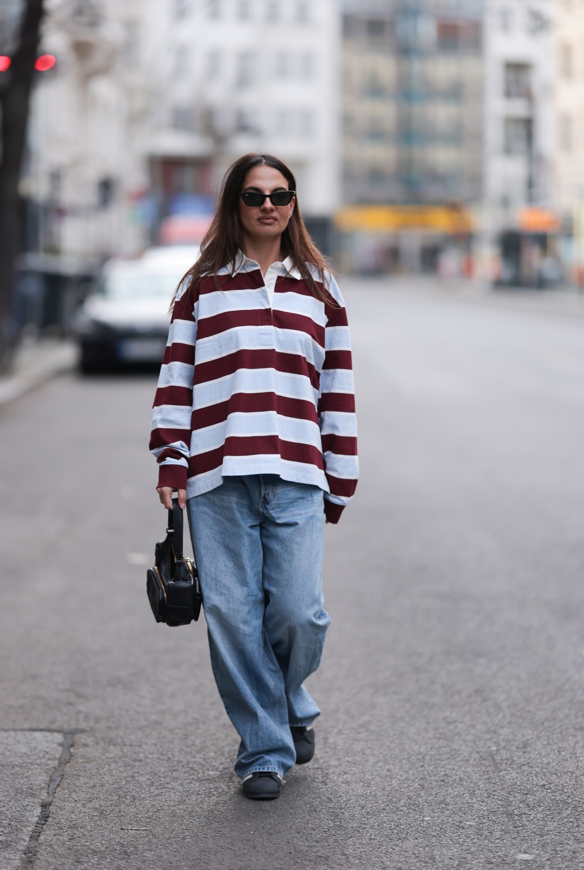 A imagem mostra uma mulher fotografada enquanto anda na rua