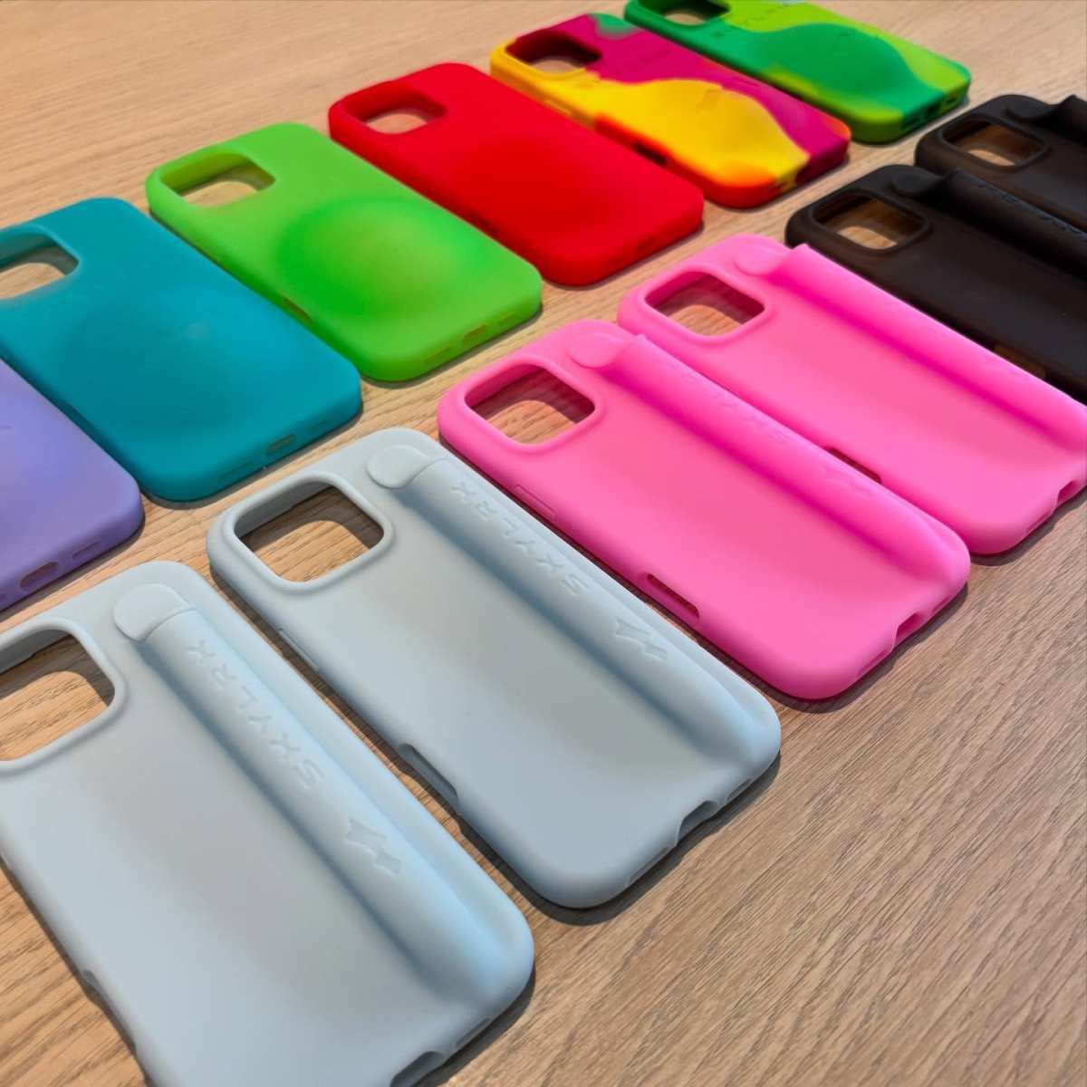 A imagem mostra diversas capinhas de celulares dispostas sob uma mesa