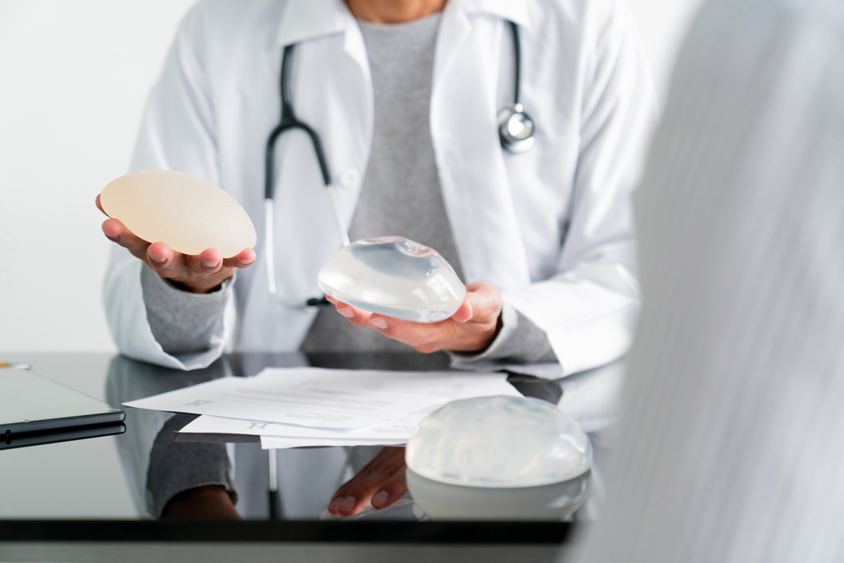 Close-up de um cirurgião plástico comparando dois tipos de implantes mamários em seu consultório - conceitos de saúde e medicina. Metrópoles