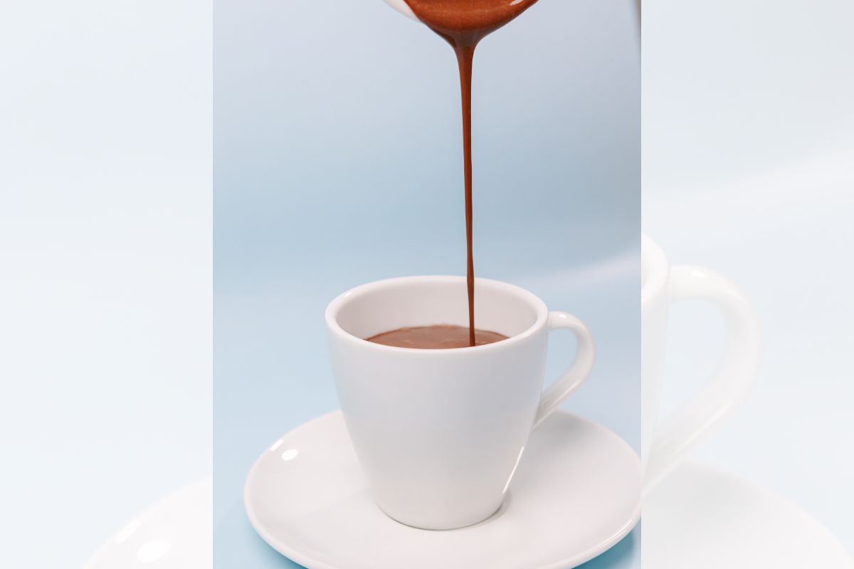 Imagem colorida de chocolate quente sendo servido na xicara 