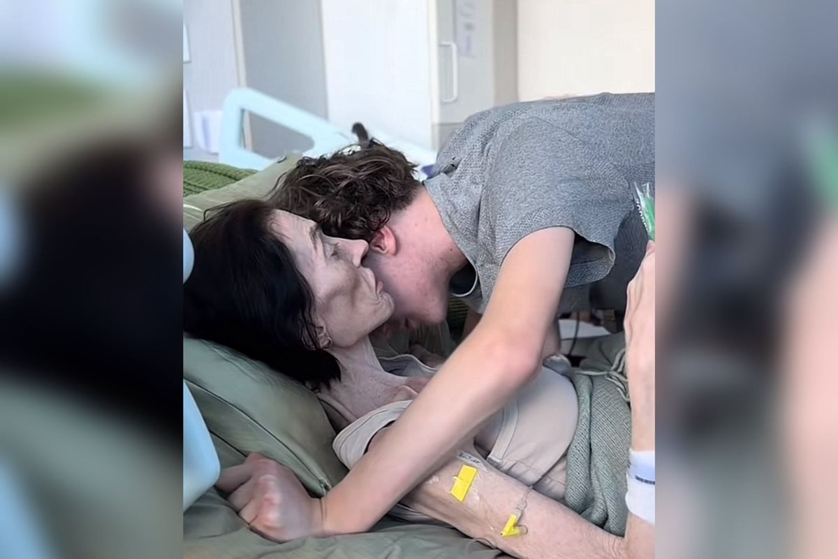 Mulher em tratamento de câncer, deitada em uma cama hospitalar abraçando uma criança - Metrópoles.