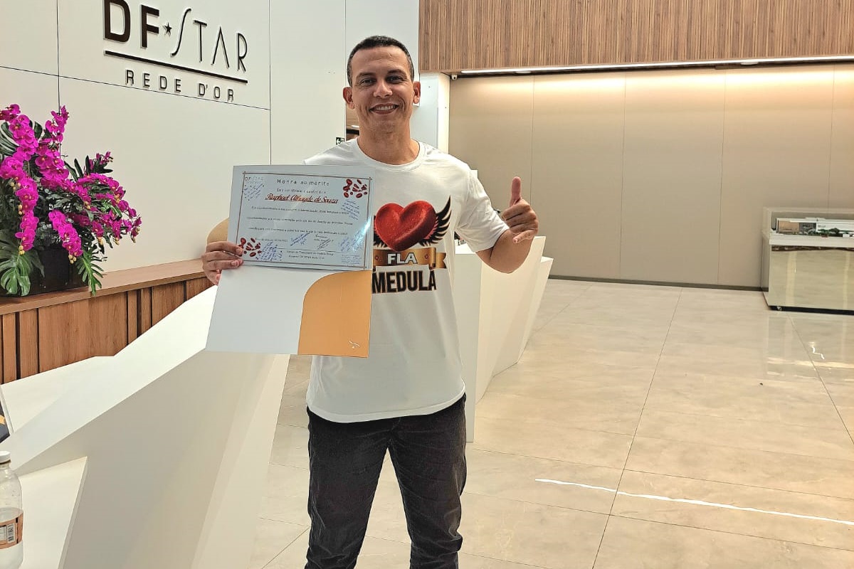 Homem segura em uma das suas mãos um certificado por doar sangue