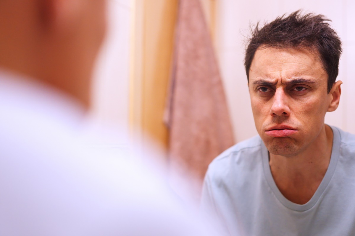 Imagem de homem estressado e cansado se olhando no espelho - Metrópoles 