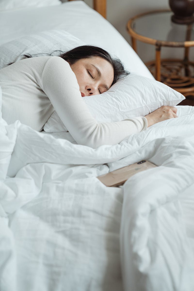 Jovem mulher asiática dormindo em cama - Metrópoles
