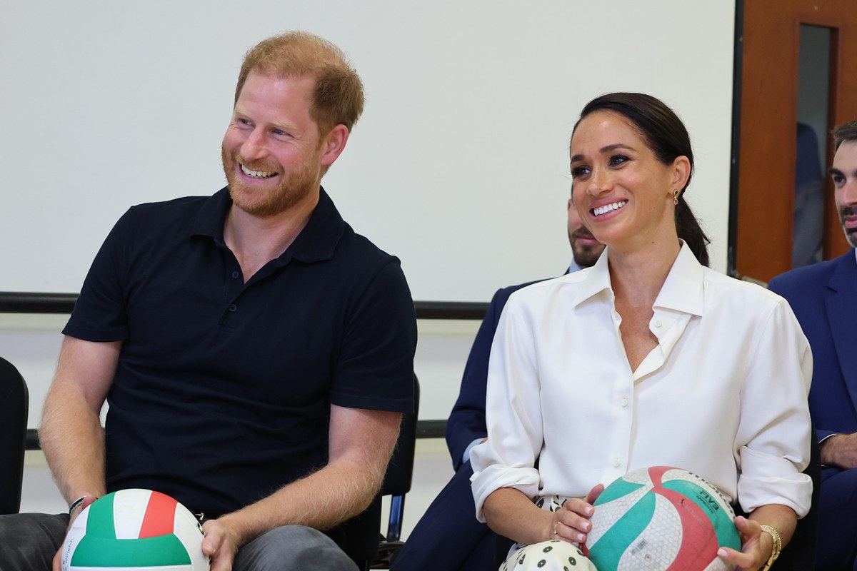 Foto colorida de homem e mulher sentados. Eles seguram uma bola - Metrópoles