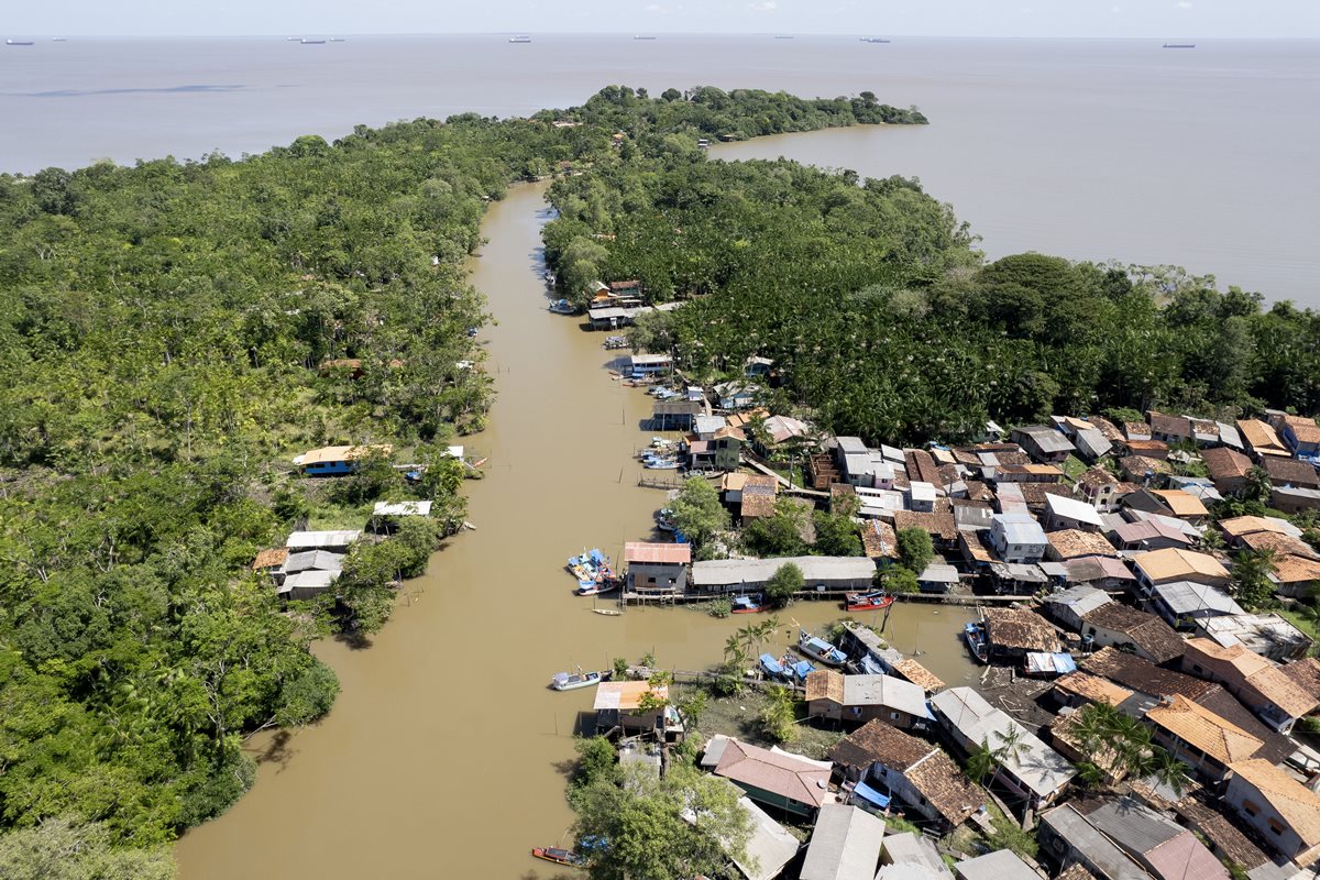 Foto colorida de população ribeirinha às margens de rio na amazõnia.