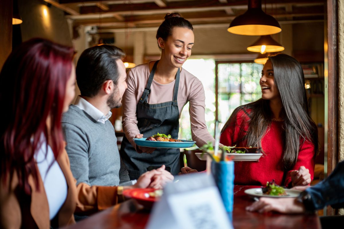 foto colorida garçom tirando os pratos da mesa em restaurante