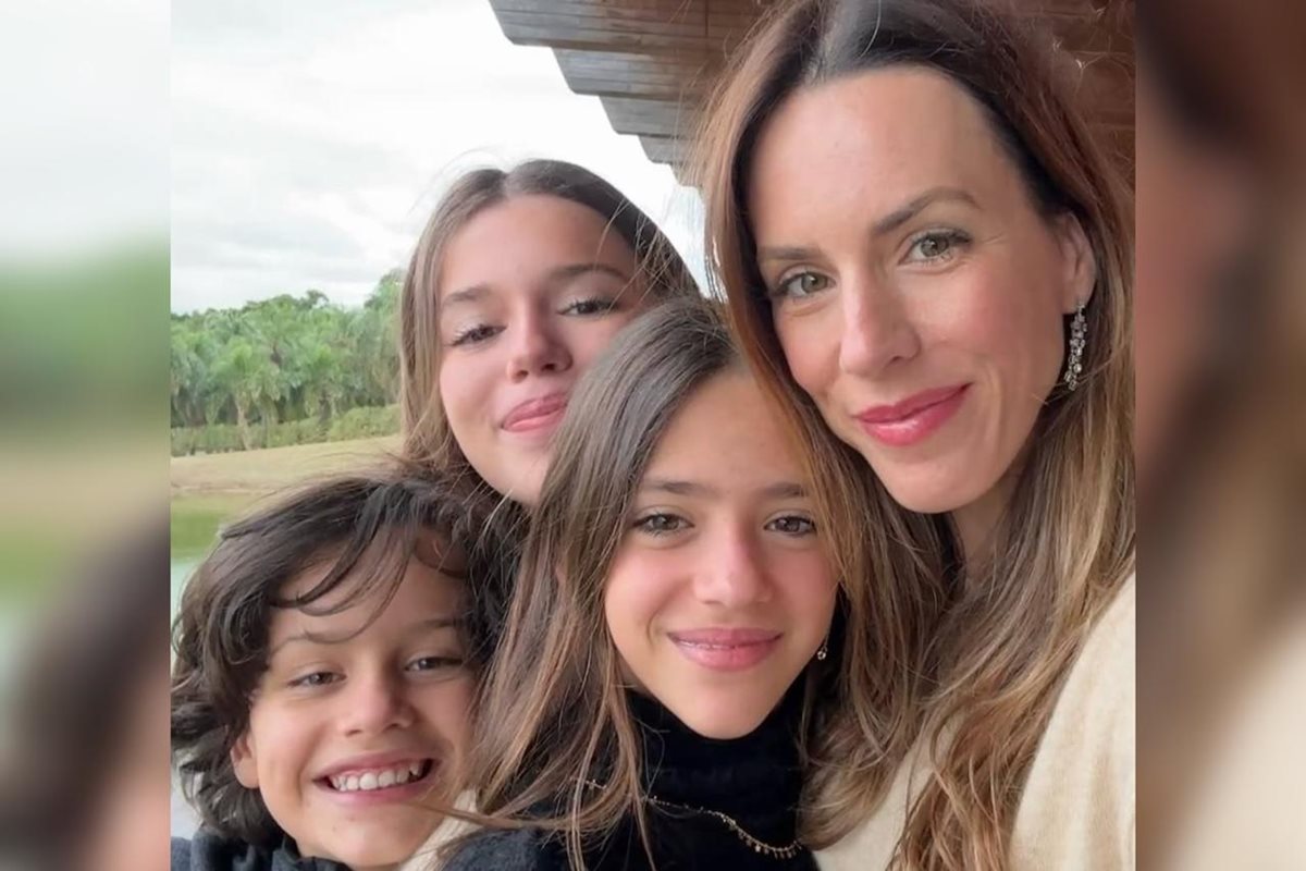 Mulher rodeada por três crianças posando para foto - Metrópoles.