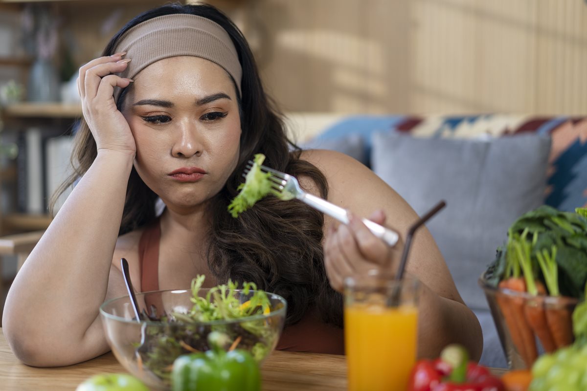 Foto colorida de mulher triste por comer alface - Metrópoles
