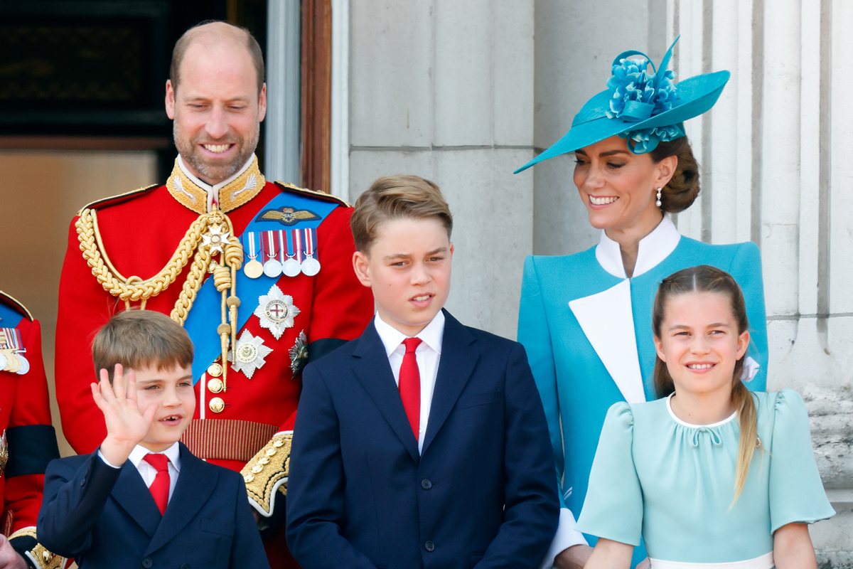 Foto colorida de homem com traje militar ao lado de mulher com roupa azul. Três crianças estão na frente do dois adultos - Metrópoles