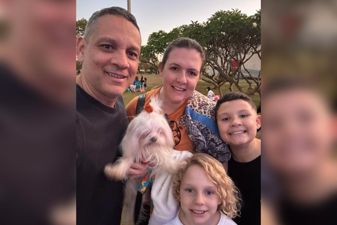 Foto colorida de família reunida em um passeio ao ar livre com o cachorro de estimação - Metrópoles