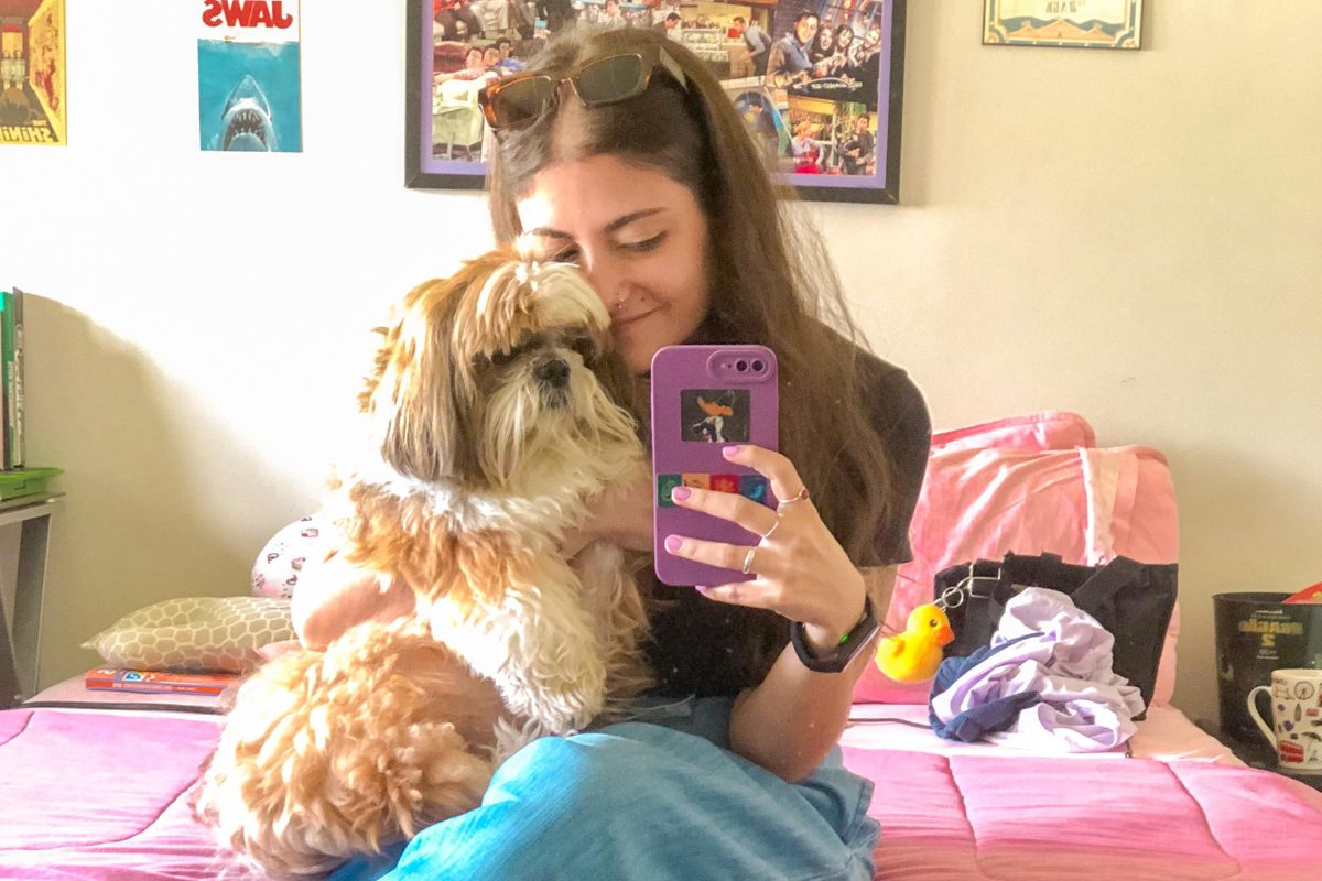 Imagem colorida de mulher abraçada à cachorro da raça shih tzu