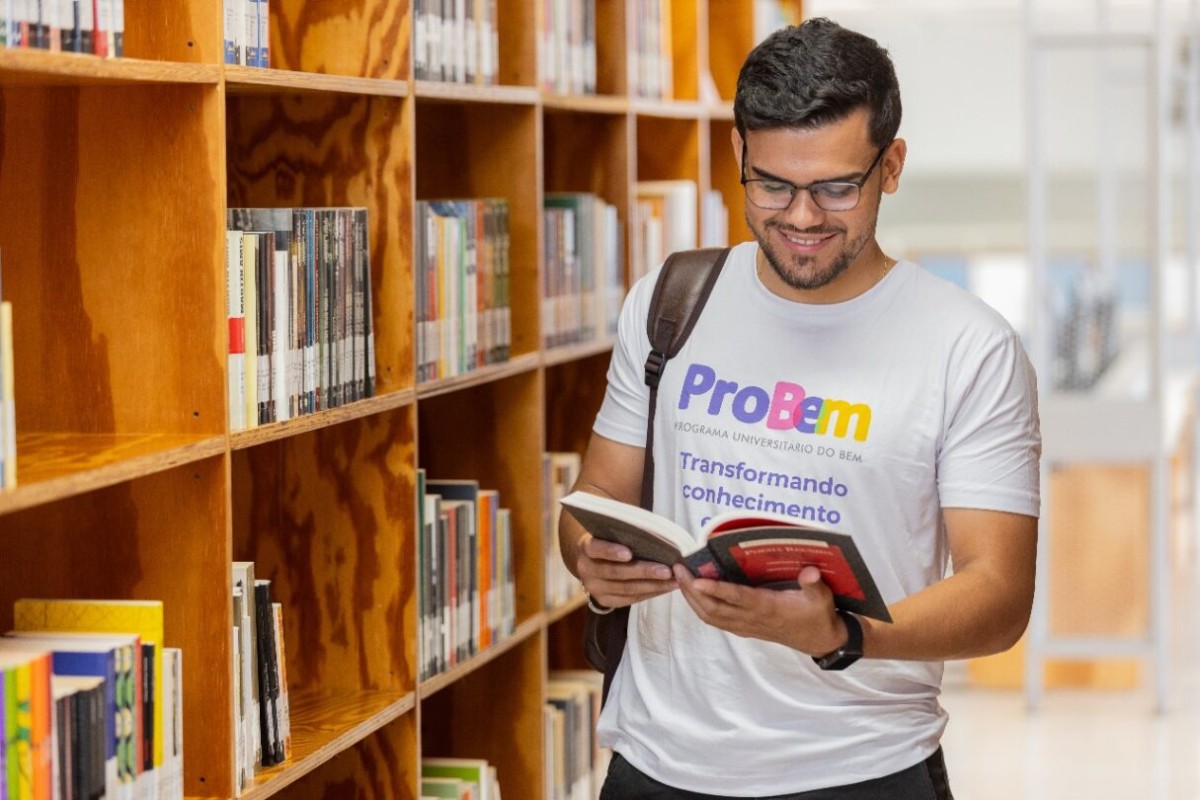 Fotografia colorida mostrando jovem estudando em biblioteca-Metrópoles
