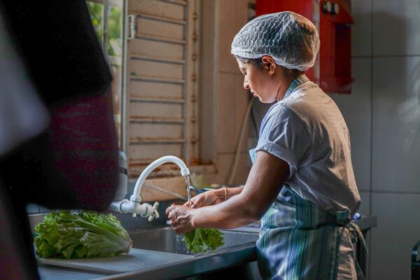 mulher lavando verduras na pia