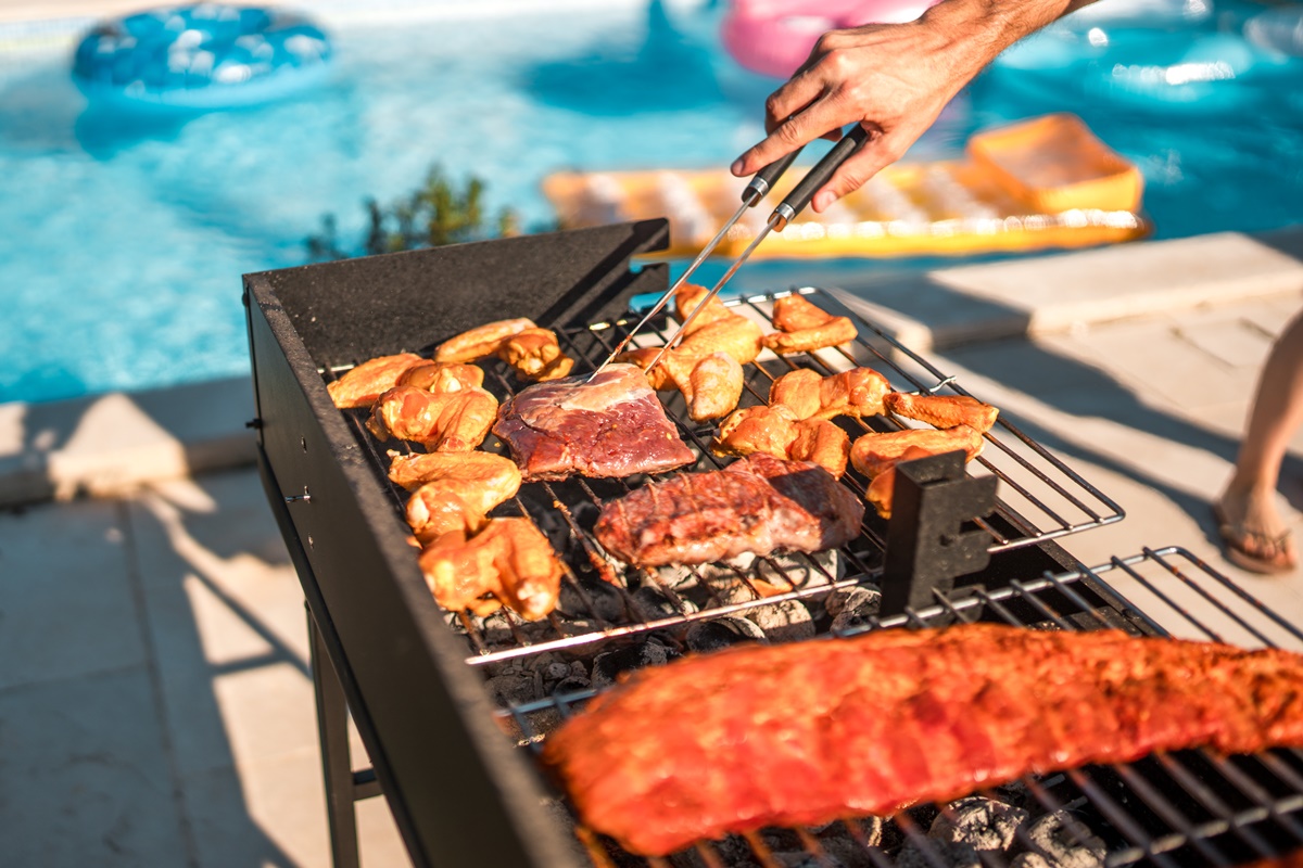 Imagem colorida de pessoa fazendo churrasco perto de piscina - Metrópoles