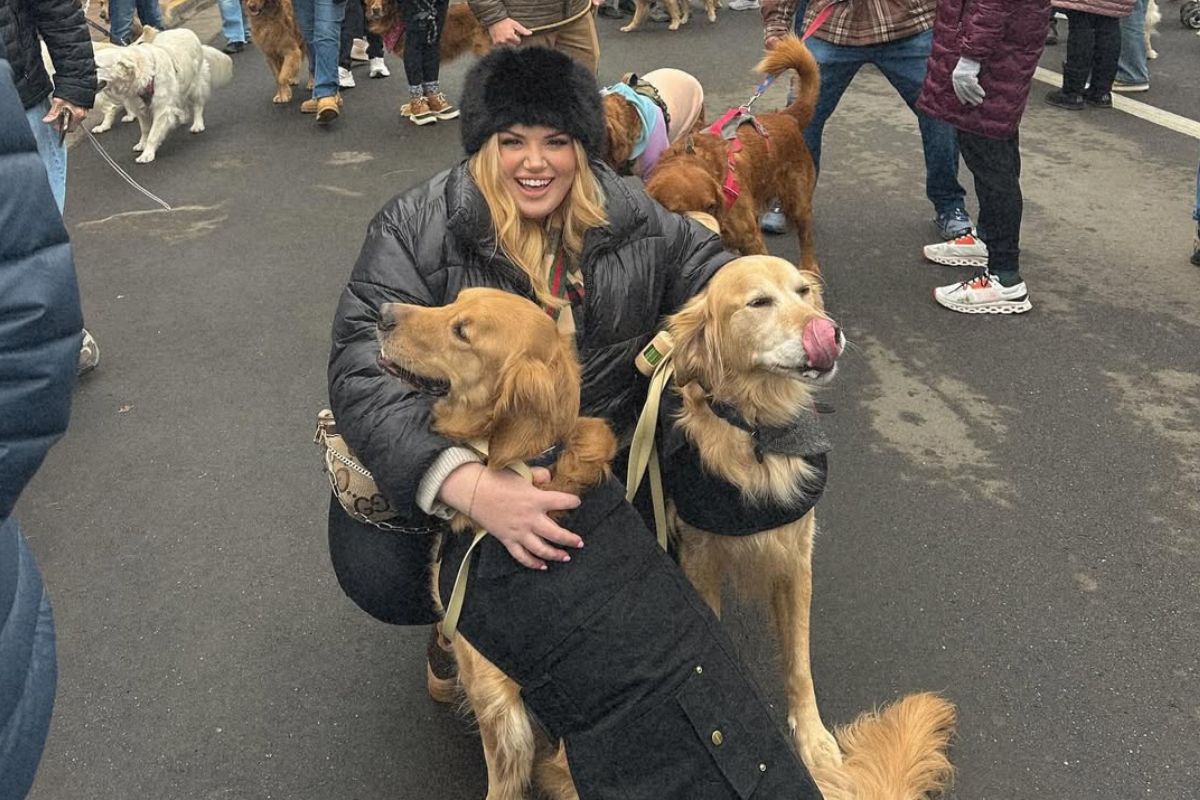 Imagem colorida de mulher abraçada com dois golden retrievers