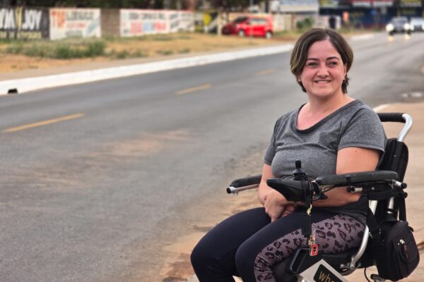 Mulher branca, cadeirante, em via de asfalto 