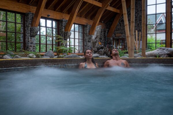 Foto colorida de um casal em uma piscina termal no Chile - Metrópoles 