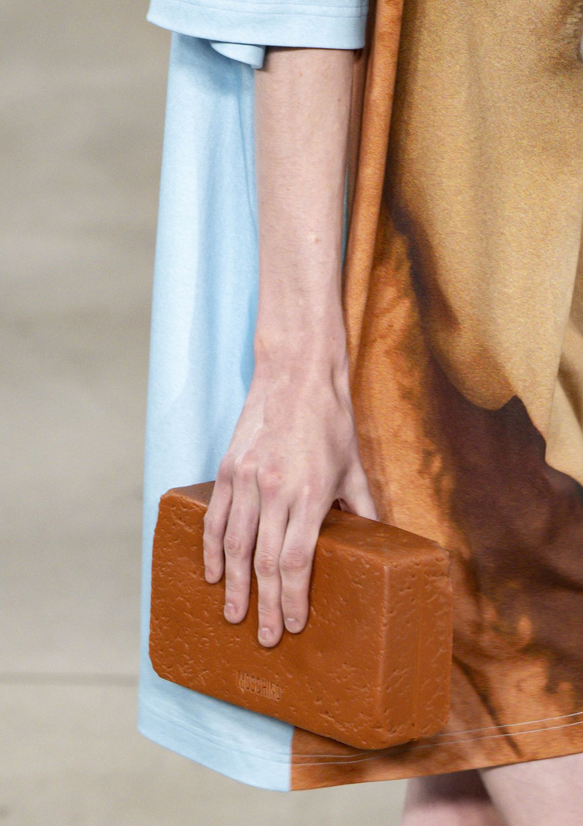 Imagem colorida de mulher carregando bolsa com forma de tijolo