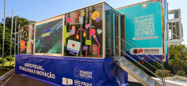Imagem externa mostra uma carreta azul estacionada, com adesivos coloridos que destacam o programa itinerante de capacitação profissional