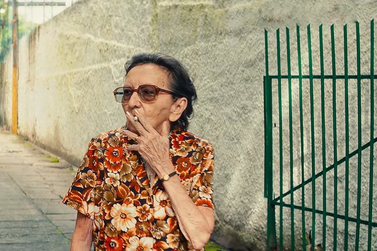 foto colorida de mulher idosa brana de cabelos curtos castanhos, usando óculos e fumando - metrópoles