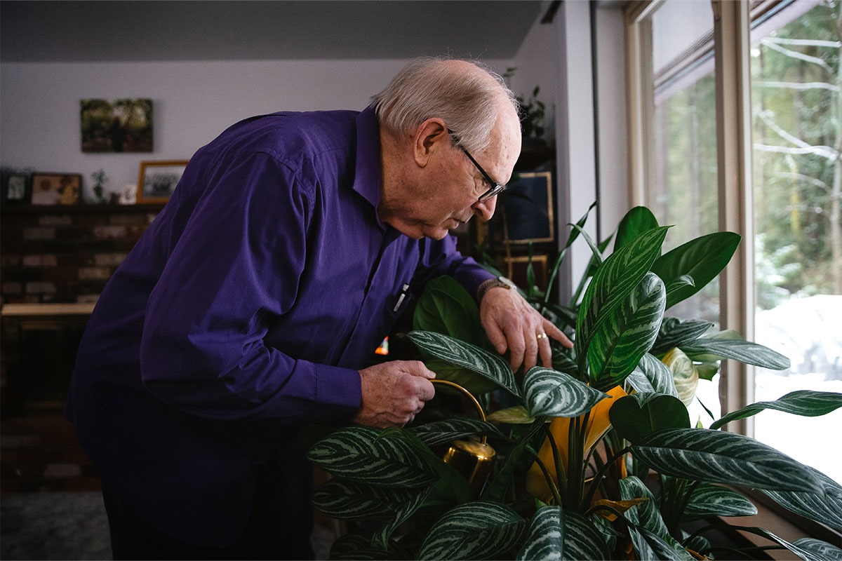 Imagem colorida mostra homem branco idoso de óculos com cabelos mais ralos regando as plantas - Metrópoles