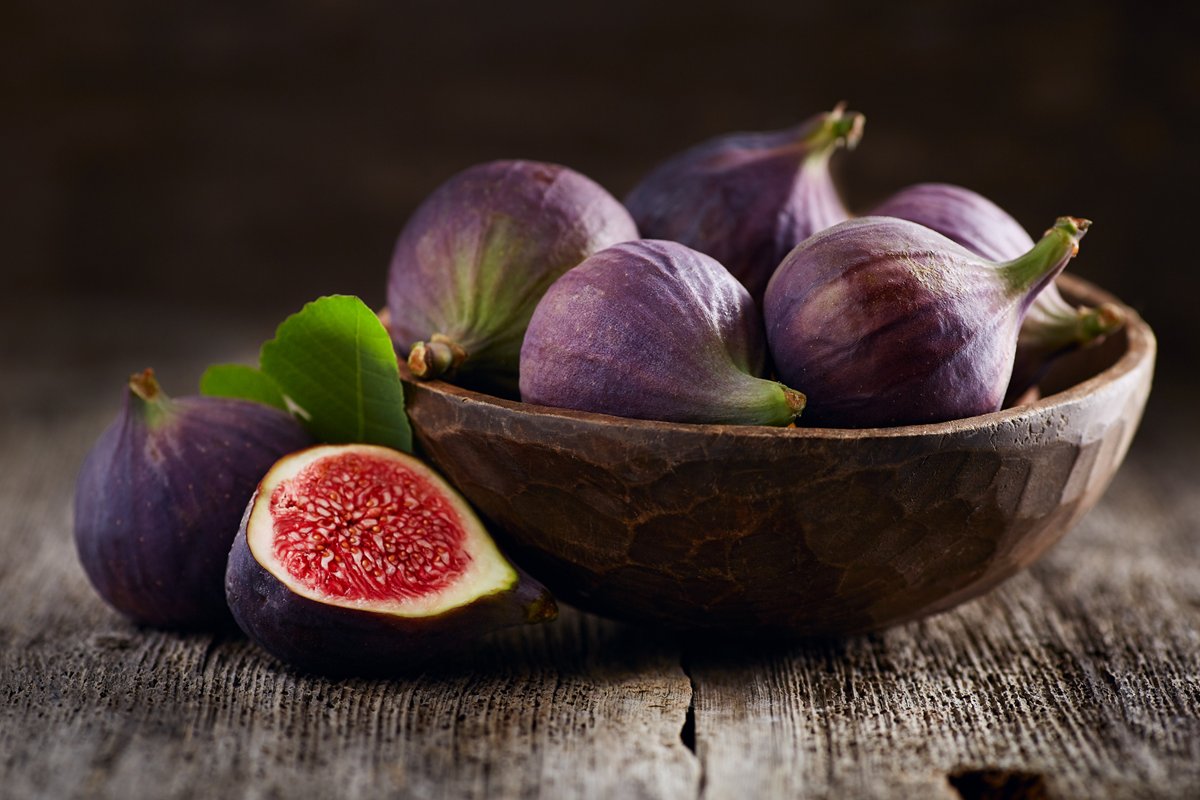 Foto colorida de figos dentro de tigela e uma fruta cortada - Metrópoles
