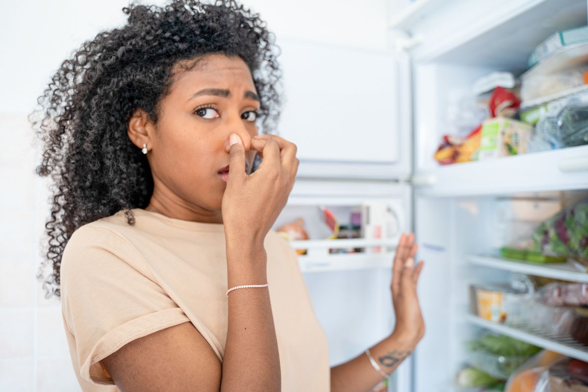 color photo of person opening refrigerator and smelling bad smell