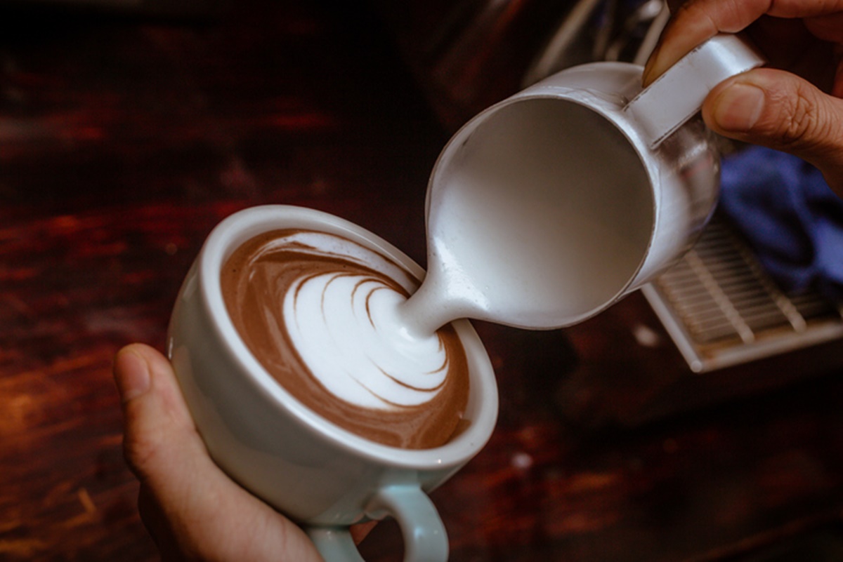 Foto colorida com mãos de homem fazendo um cappuccino - Metrópoles