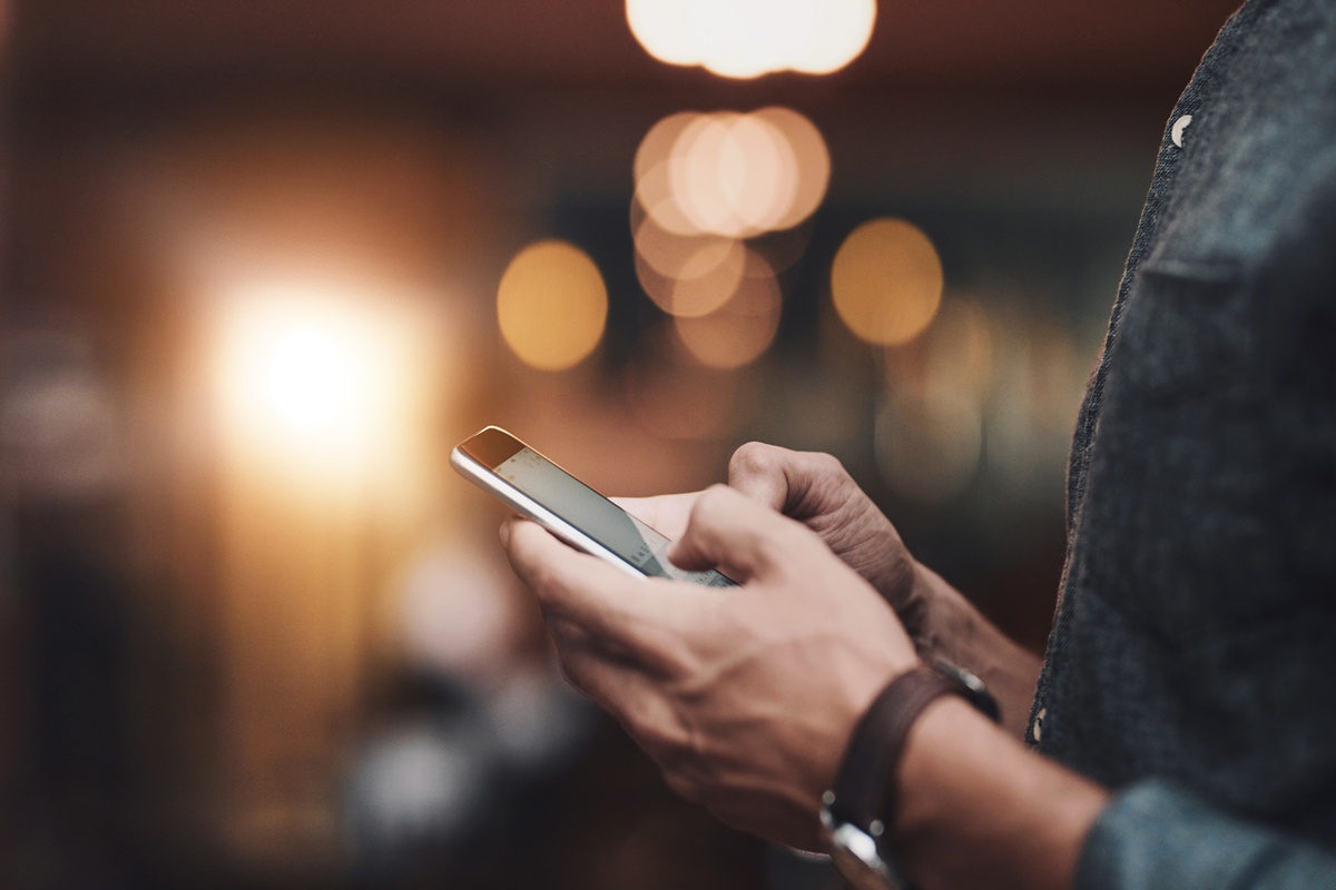 Homem digitando em celular em restaurante