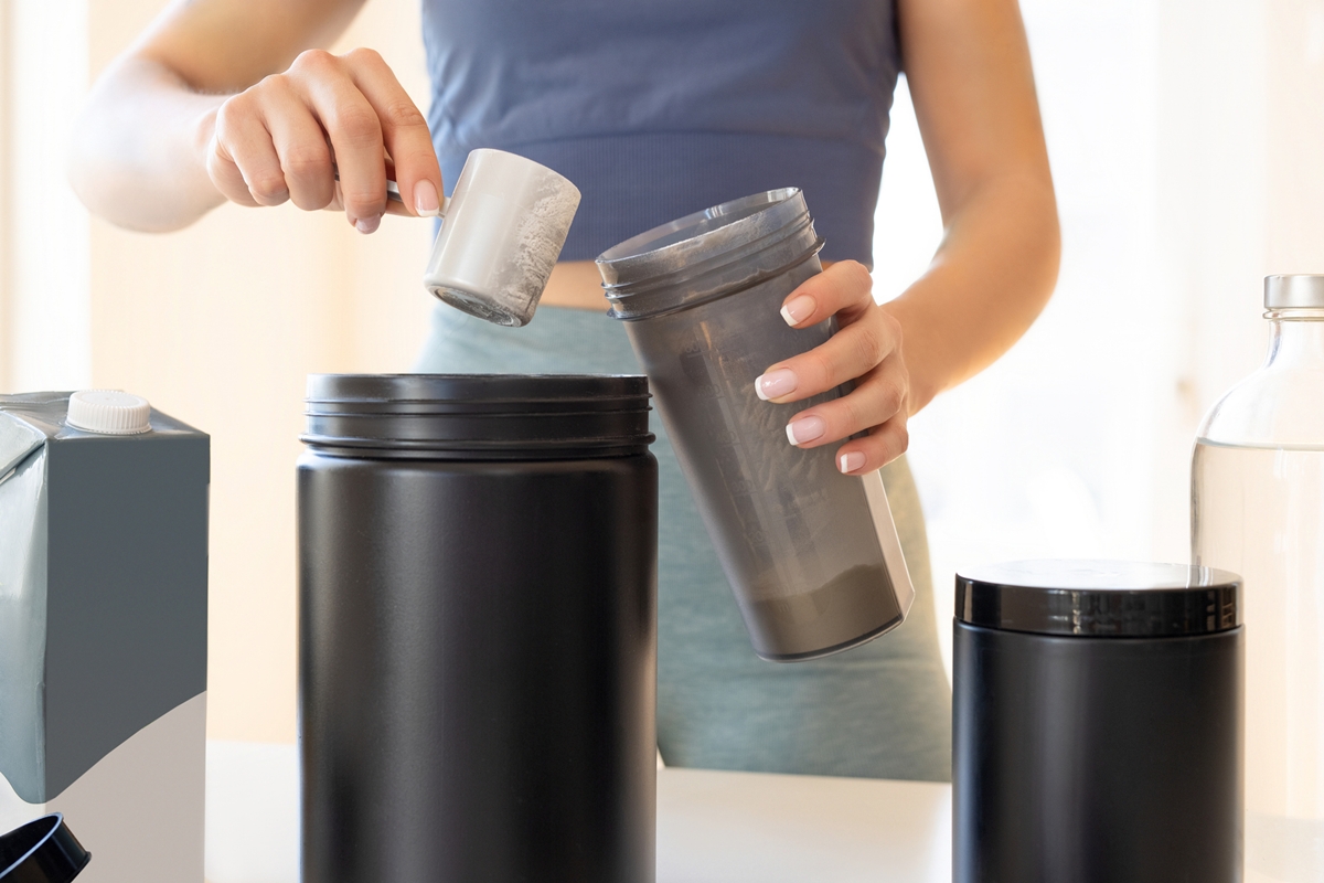 Mãos de mulher preparando bebida com Whey Protein - Metrópoles