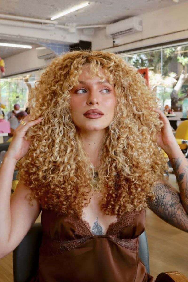 Foto colorida de uma mulher loira cacheada - Metrópoles