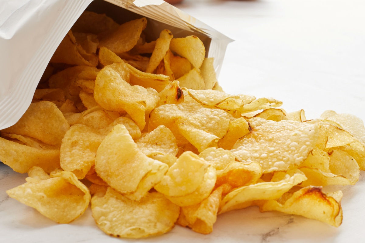 Embalagem branca com salgadinho de cor amarela derramado - Metrópoles.